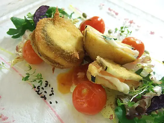 Panierte Auberginentoast mit Tomaten, Mozzarella und Basilikum auf sautierten Kirschtomaten