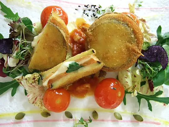 Panierte Auberginentoast mit Tomaten, Mozzarella und Basilikum auf sautierten Kirschtomaten