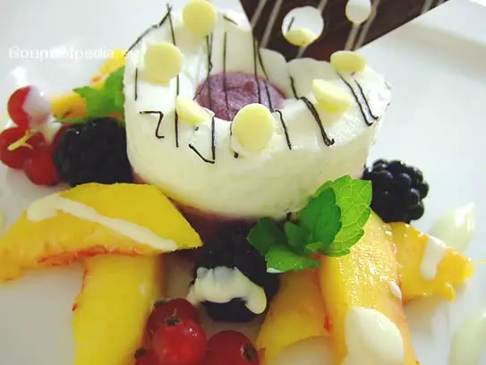 Mousse von der Blaubeere und Vanille auf marinierten Pfirsichen und Waldbeeren