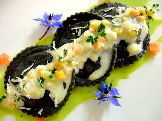 Schwarze Ravioli mit Gemüsefüllung auf feiner Petersiliensauce