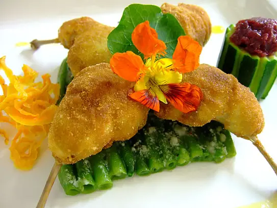 Gefüllte frittierte Wachtelkeulen auf grünen Bohnen und gedünsteten Blaukraut in der Zucchini